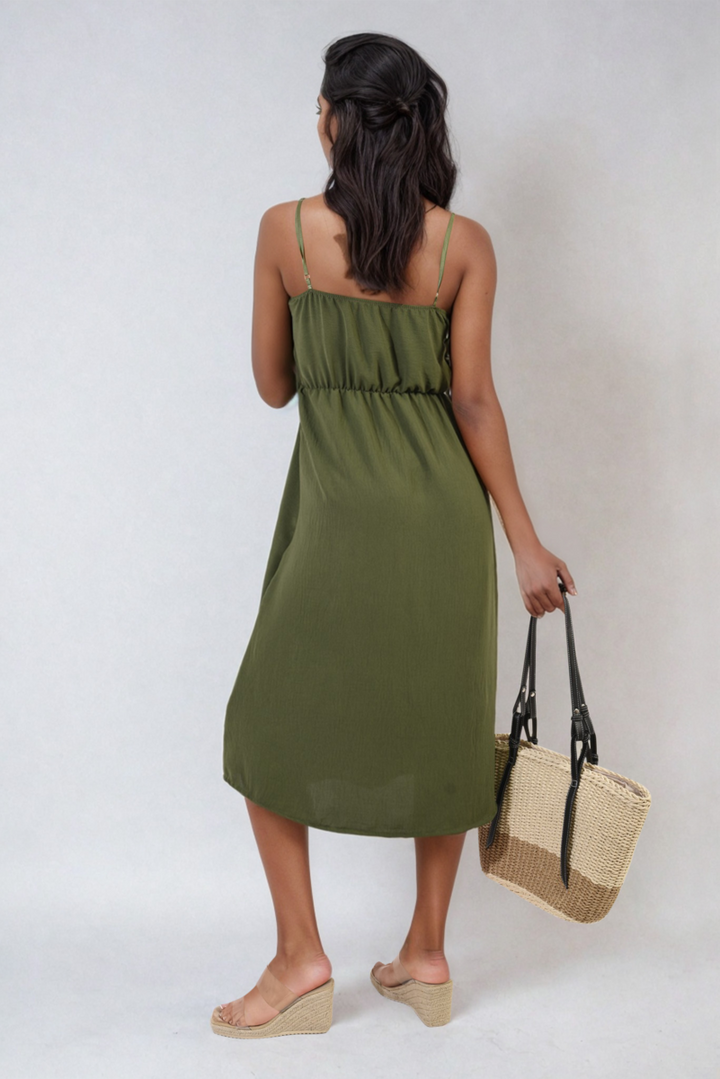 Woman in a green Button Front Strappy Midi Dress holding a straw bag, showcasing a stylish look ideal for summer outings and holiday occasions.