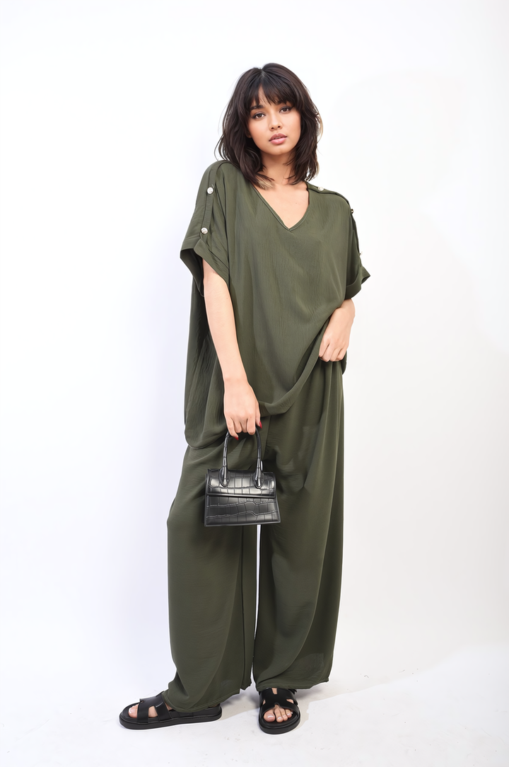 Woman wearing the Button Detail V Neck Loose Top and Wide Leg Trouser Co-ord Set, holding a black purse, showcasing stylish comfort for holiday occasions.