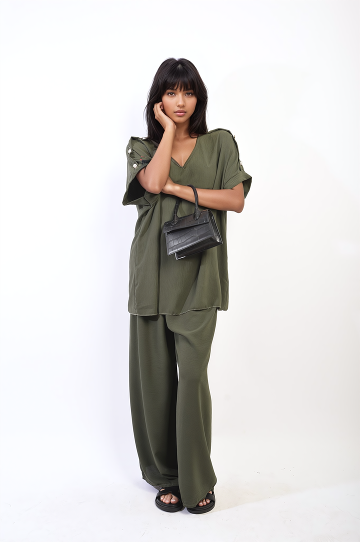 Woman in Button Detail V Neck Loose Top and Wide Leg Trouser Co-ord Set, holding a handbag, with black sandals. Ideal for stylish summer outings.