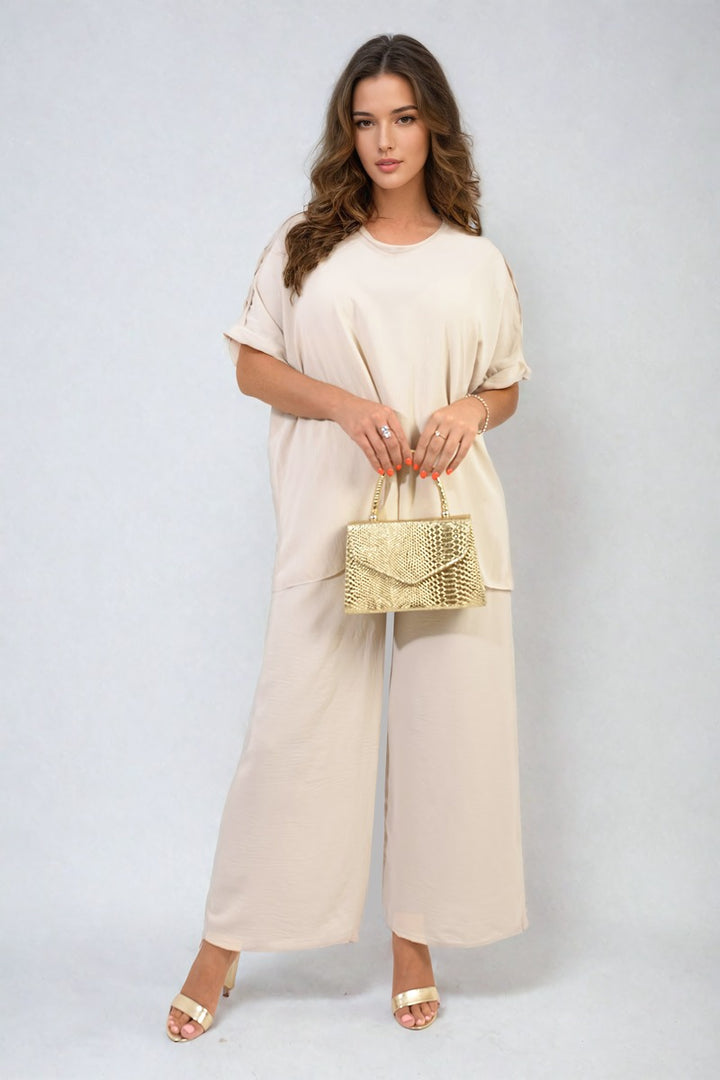 Woman holding a gold purse wearing the Button Detail V Neck Loose Top and Wide Leg Trouser Co-ord Set, showcasing summer sophistication and effortless style.