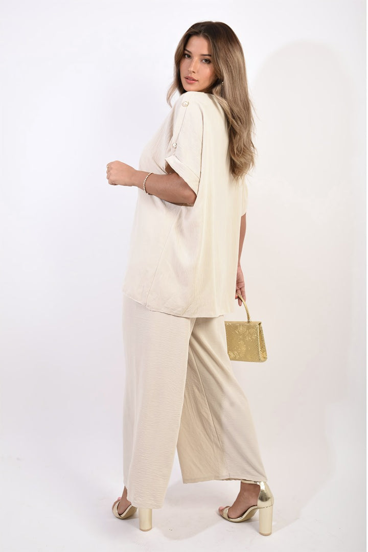 Woman wearing Button Detail V Neck Loose Top and Wide Leg Trouser Co-ord Set, holding a gold purse, showcasing summer sophistication and style.