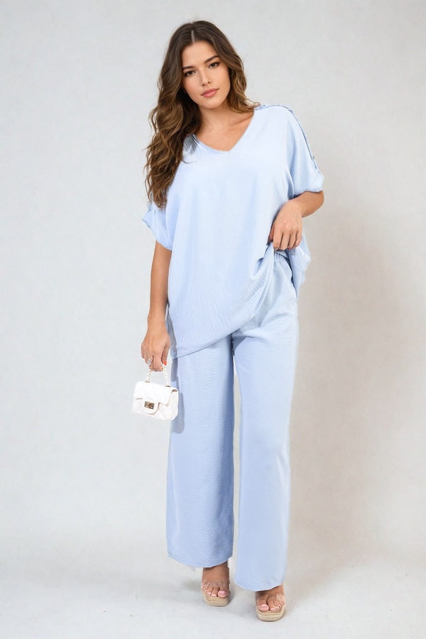 Riley Button Detail V Neck Loose Top and Wide Leg Trouser Co-ord Set, showcased by a woman holding a white purse, epitomizes summer sophistication.