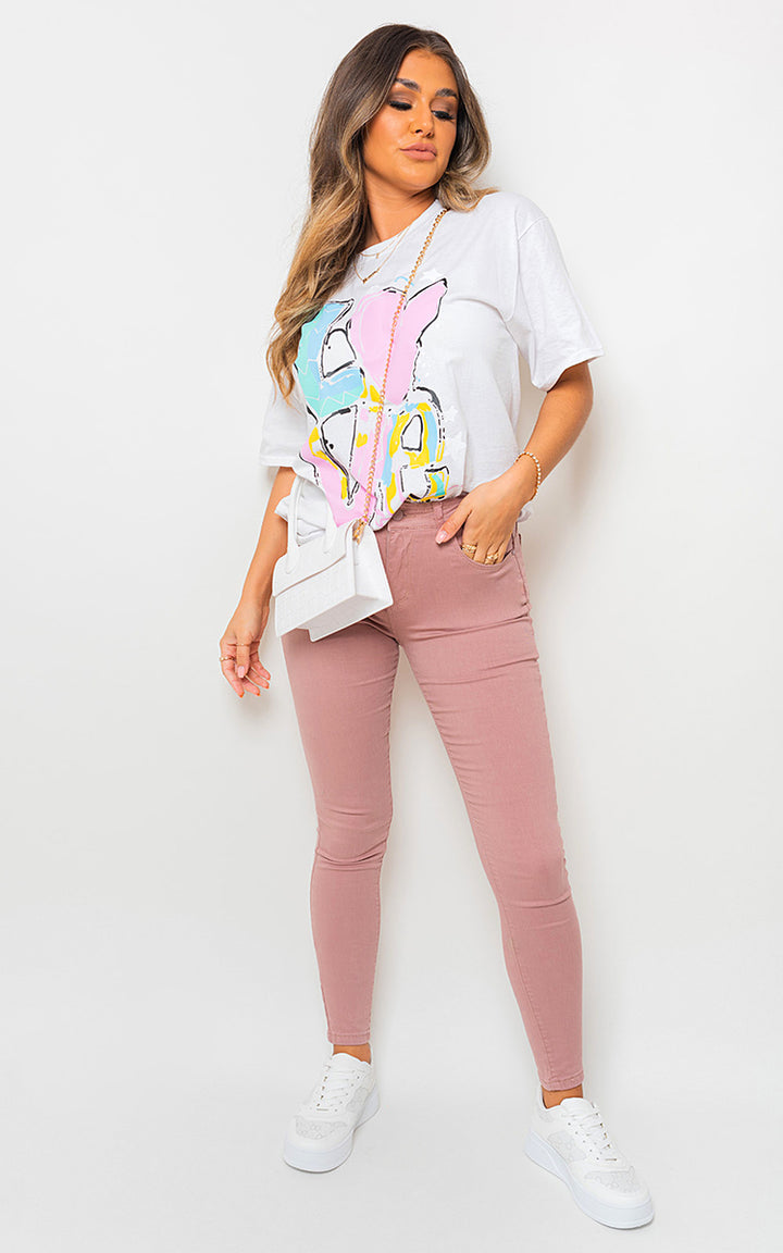 Woman wearing high waisted skinny fit jeans, styled with a white shirt and pink pants, showcasing the flattering silhouette and modern fit of the jeans.