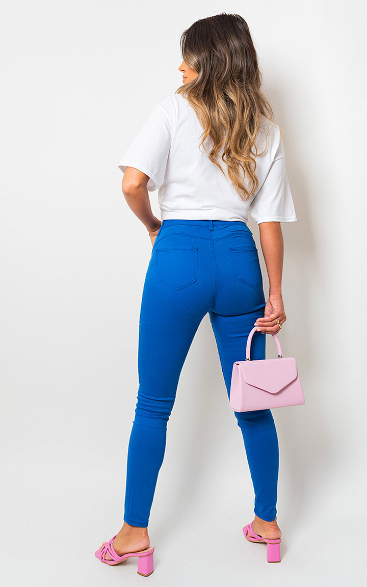 Woman in blue jeans holding a pink purse, showcasing the Robyn High Waisted Skinny Fit Jeans, highlighting their flattering and modern design.