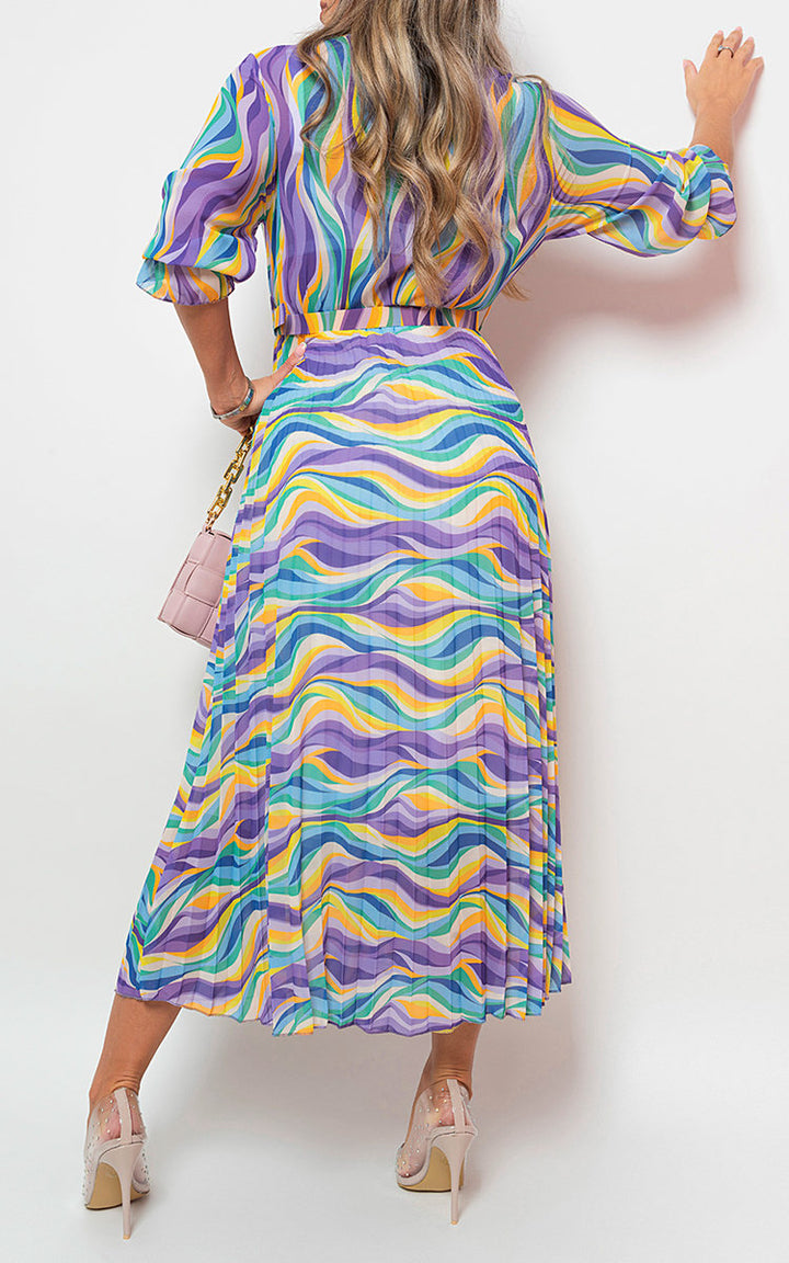 Woman wearing a Long Sleeve Printed Maxi Dress with Belt Detail, accessorized with a pink purse, showcasing a stylish and versatile look from Holiday-clothes.co.uk.