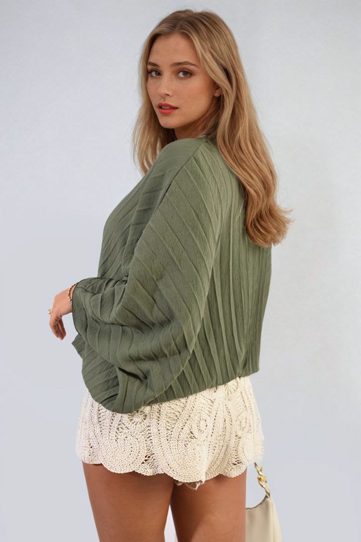 Woman wearing a Batwing Oversized Pleated Top, showcasing its dramatic batwing sleeves and modern pleated design, perfect for stylish, versatile wear.