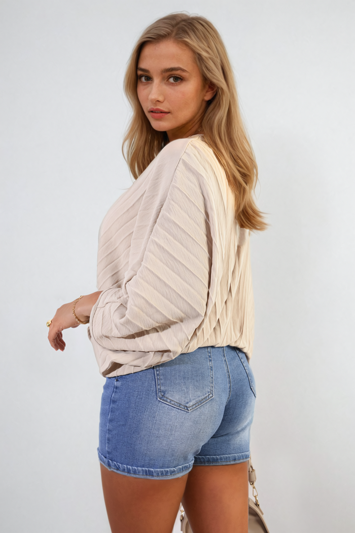 Woman modeling the Rowena Batwing Oversized Pleated Top, showcasing its dramatic batwing sleeves and modern pleated design, ideal for stylish versatility.