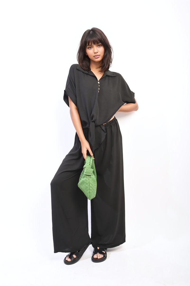 Woman in stylish Tie Front Top and Wide Leg Pants Co-ord Set, holding a green purse, showcasing a chic and comfortable ensemble.