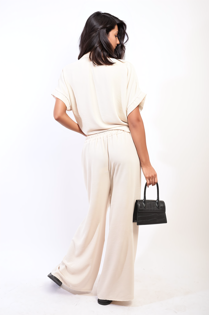 Woman in white outfit holding a black purse, wearing Tie Front Top and Wide Leg Pants Co-ord Set, embodying stylish sophistication.