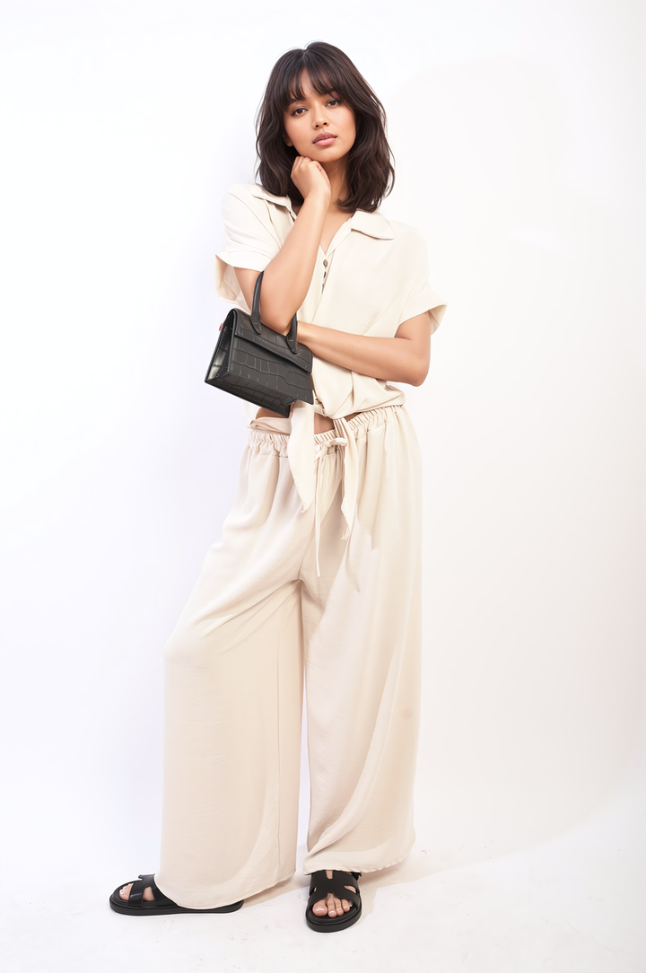 Woman wearing Tie Front Top and Wide Leg Pants Co-ord Set, holding a black purse, showcasing a stylish ensemble from Holiday Clothes UK.