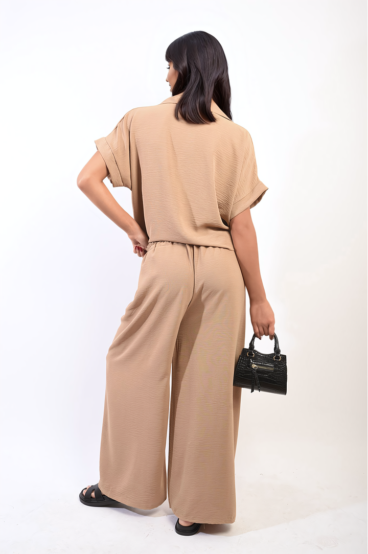 Woman in a beige Tie Front Top and Wide Leg Pants Co-ord Set, holding a black purse, embodying style and comfort from Holiday Clothes UK.