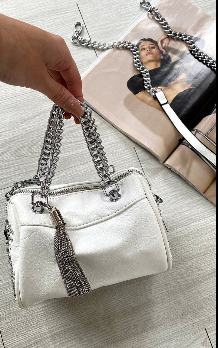 Hand holding the Studded with Chain Detail Handbag, showcasing its faux leather and silver chain accents, ideal for adding luxury to any outfit.