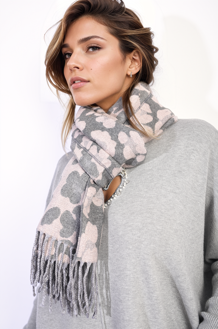 Woman wearing Saira Animal Print Scarf with Tassel, showcasing bold design and playful tassels, highlighting its stylish impact and versatility for holiday or everyday wear.