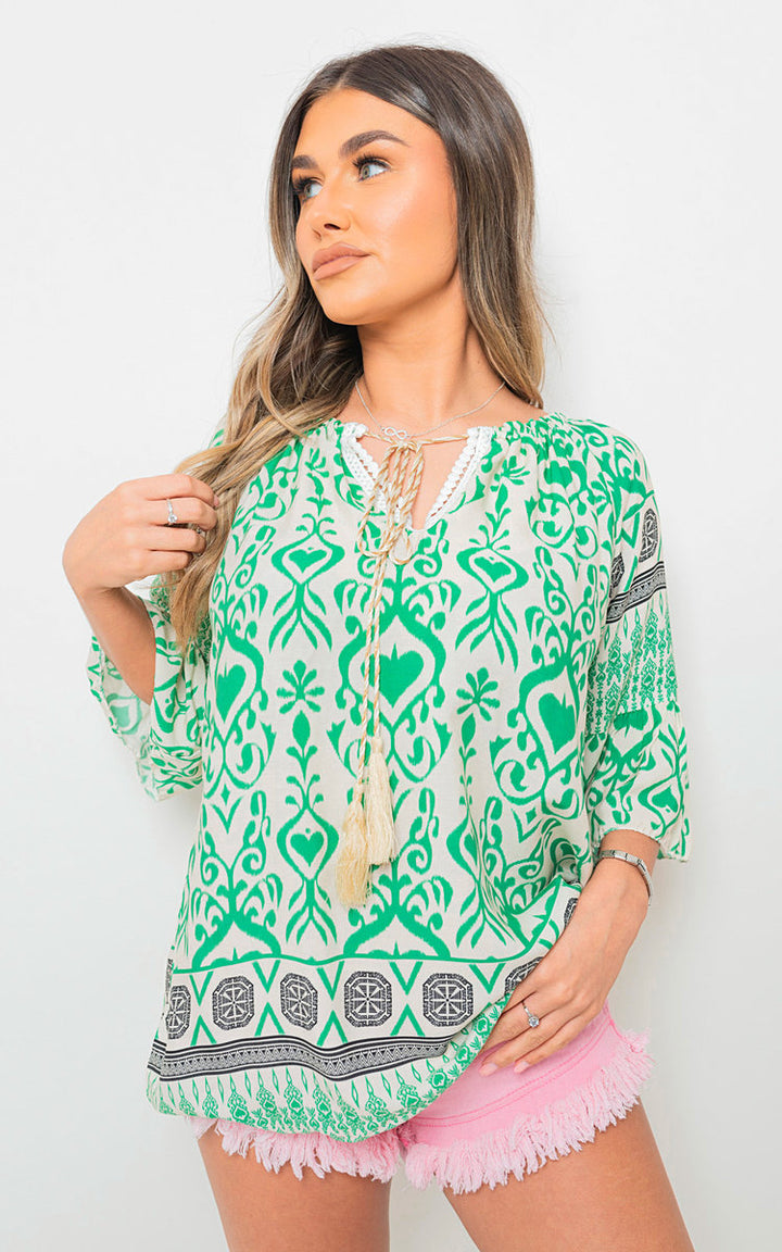 Boho Printed Tassel Tie Neck Long Sleeve Loose Top on model, showcasing its flowy silhouette and intricate boho patterns.