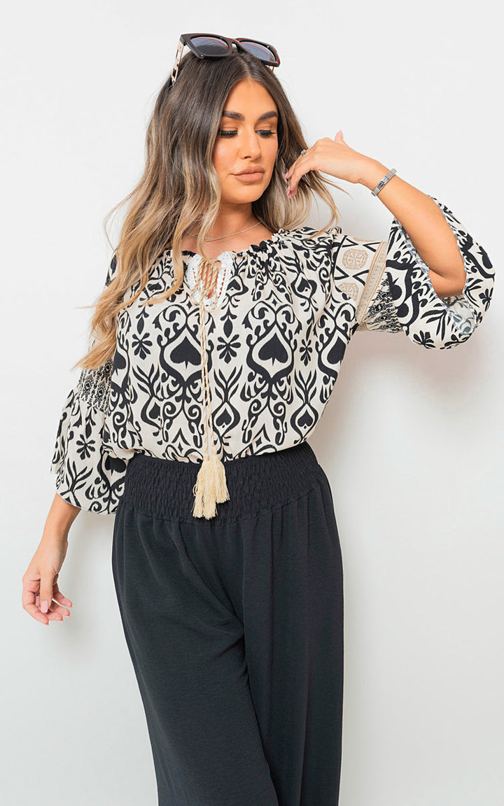 Woman wearing Boho Printed Tassel Tie Neck Long Sleeve Loose Top, showcasing bohemian style with intricate patterns and adjustable tassel neckline.