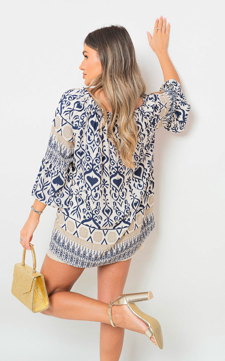 Boho Printed Tassel Tie Neck Long Sleeve Loose Top worn by a woman, showcasing its boho print and tassel detailing, paired with sandals and a handbag.