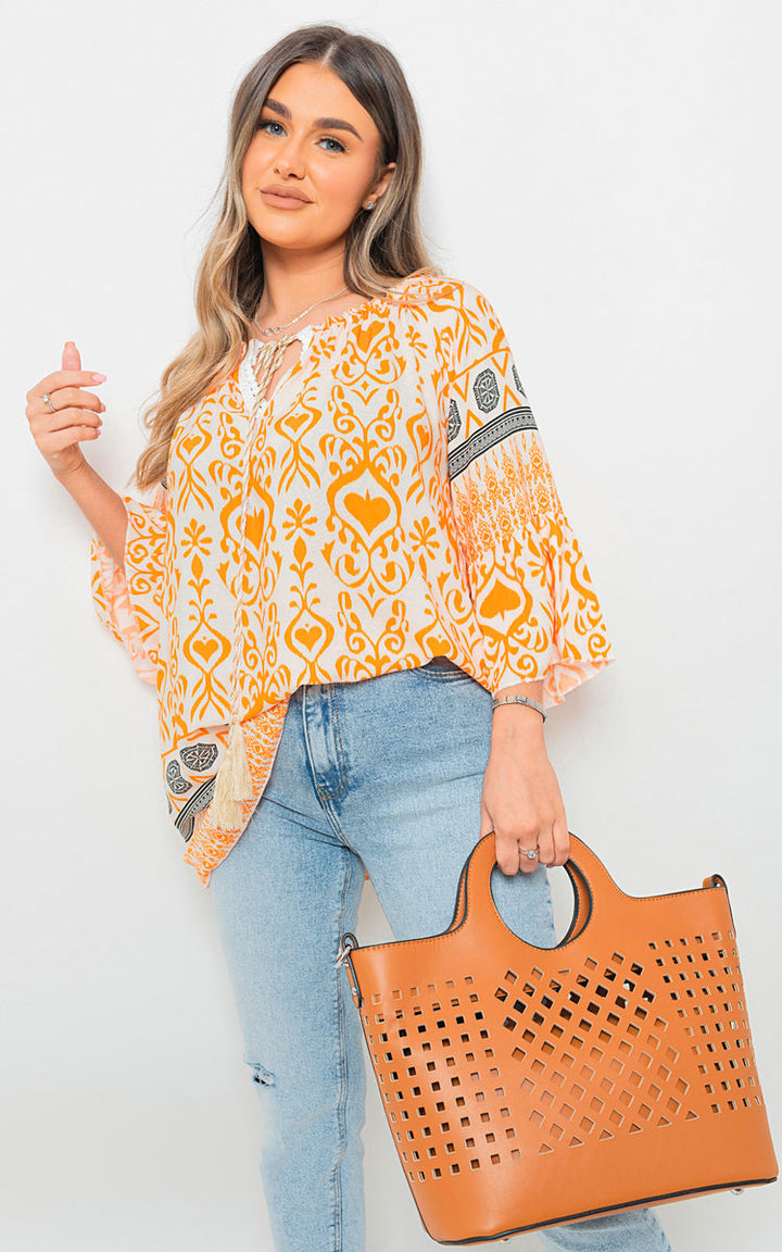 Woman holding Boho Printed Tassel Tie Neck Long Sleeve Loose Top, showcasing its boho-inspired print and tassel detail, perfect for casual or festival wear.