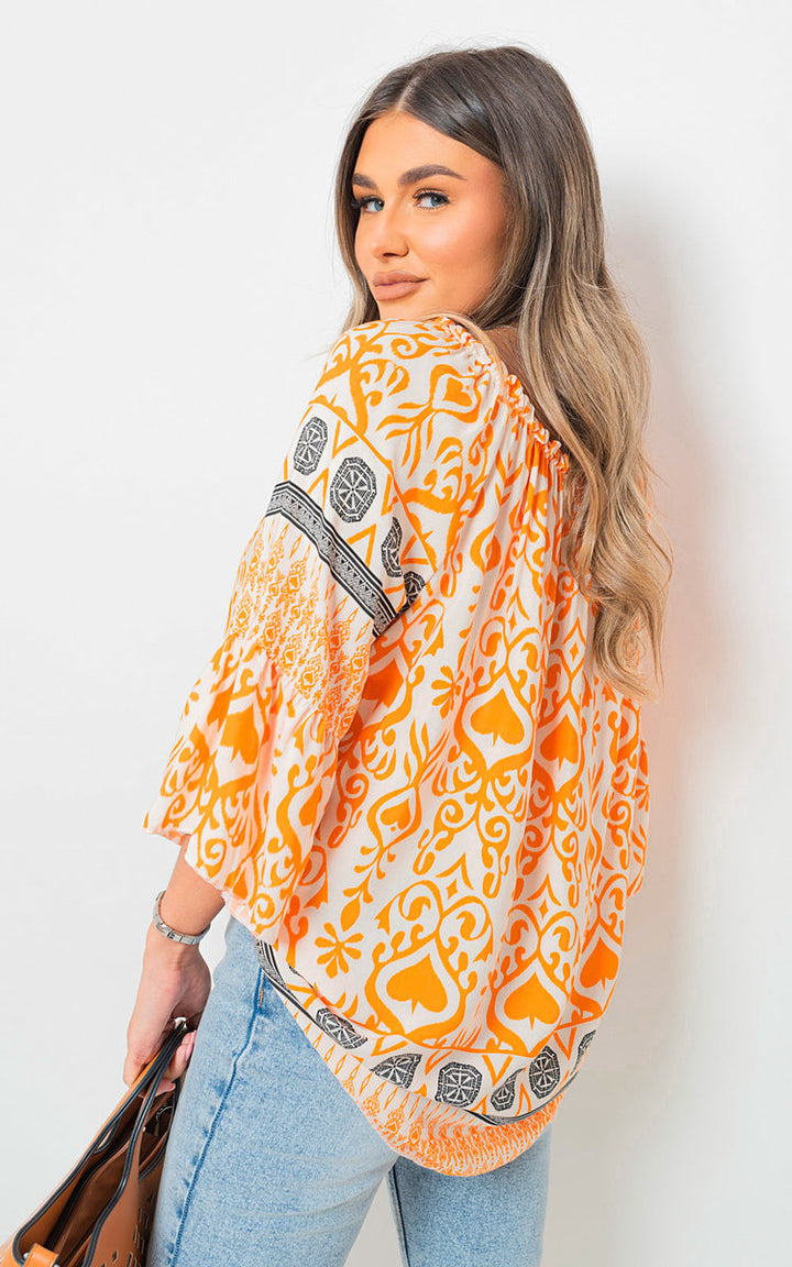 Woman wearing Boho Printed Tassel Tie Neck Long Sleeve Loose Top, accessorized with a handbag, showcasing a stylish, casual look suitable for various occasions.