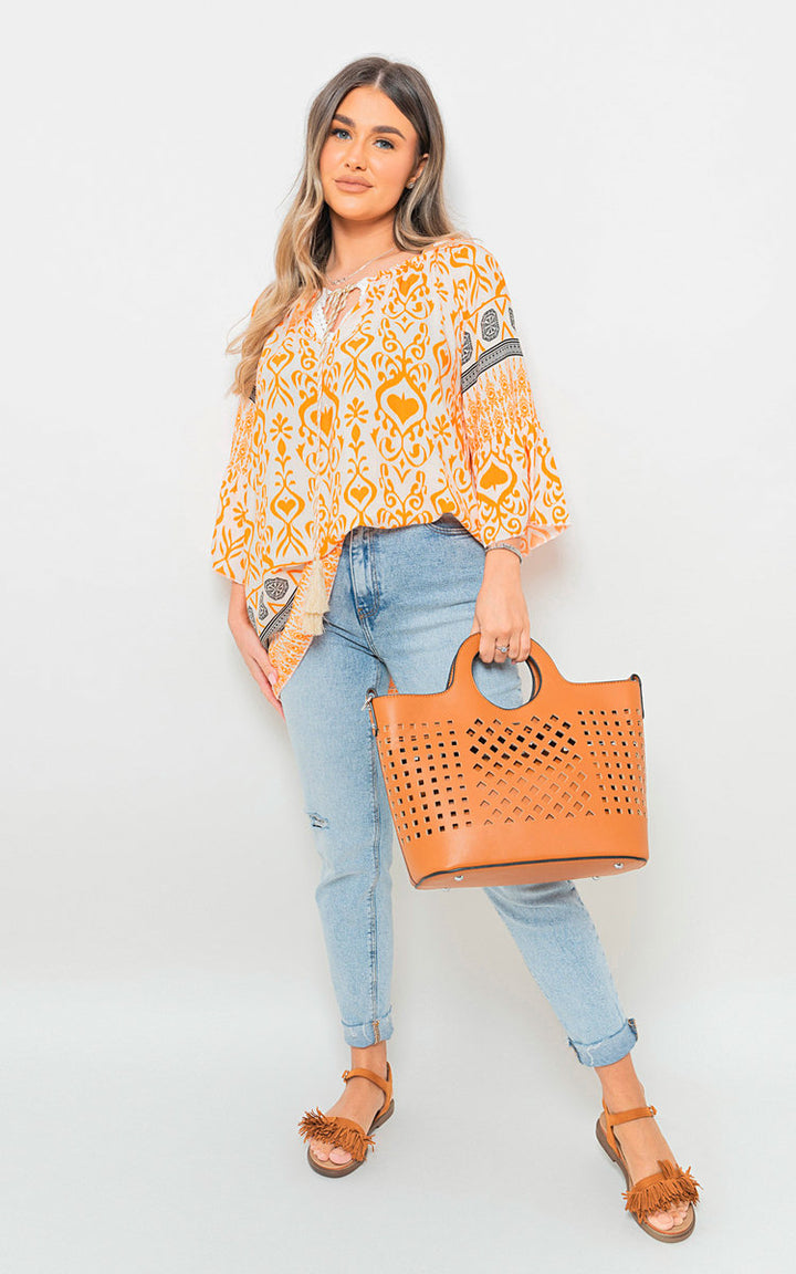 Woman holding Boho Printed Tassel Tie Neck Long Sleeve Loose Tops, showcasing its boho-inspired design and tassel neck detail. Perfect for stylish holiday and everyday wear.