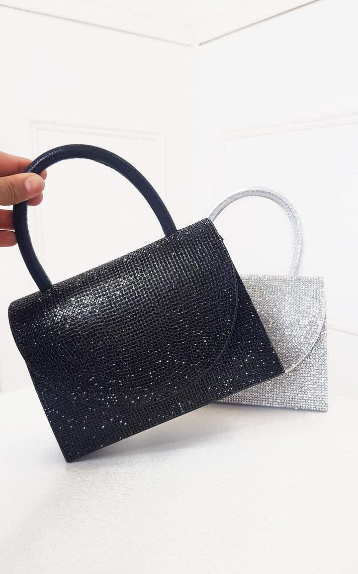 Diamante Embellished Handbag with black and silver design, held by a hand, featuring a detachable shoulder strap and magnetic closure. Ideal for special occasions.