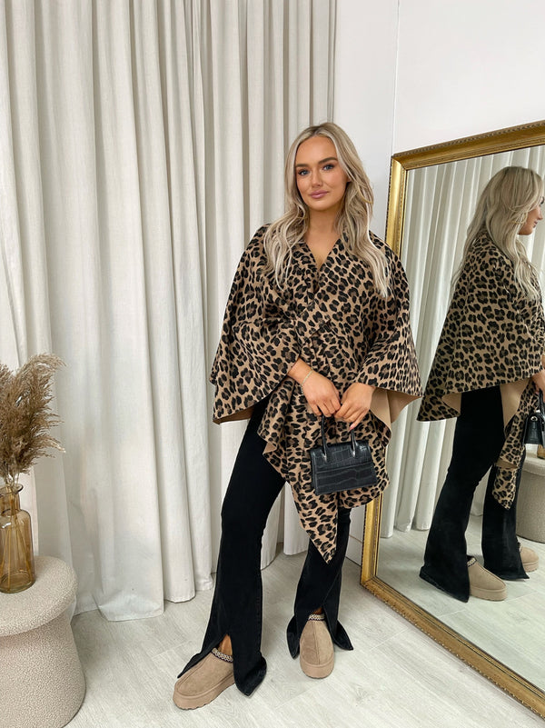 Woman wearing the Savana Oversized Cape Jacket, showcasing its chic, layered design while holding a purse in front of a mirror.