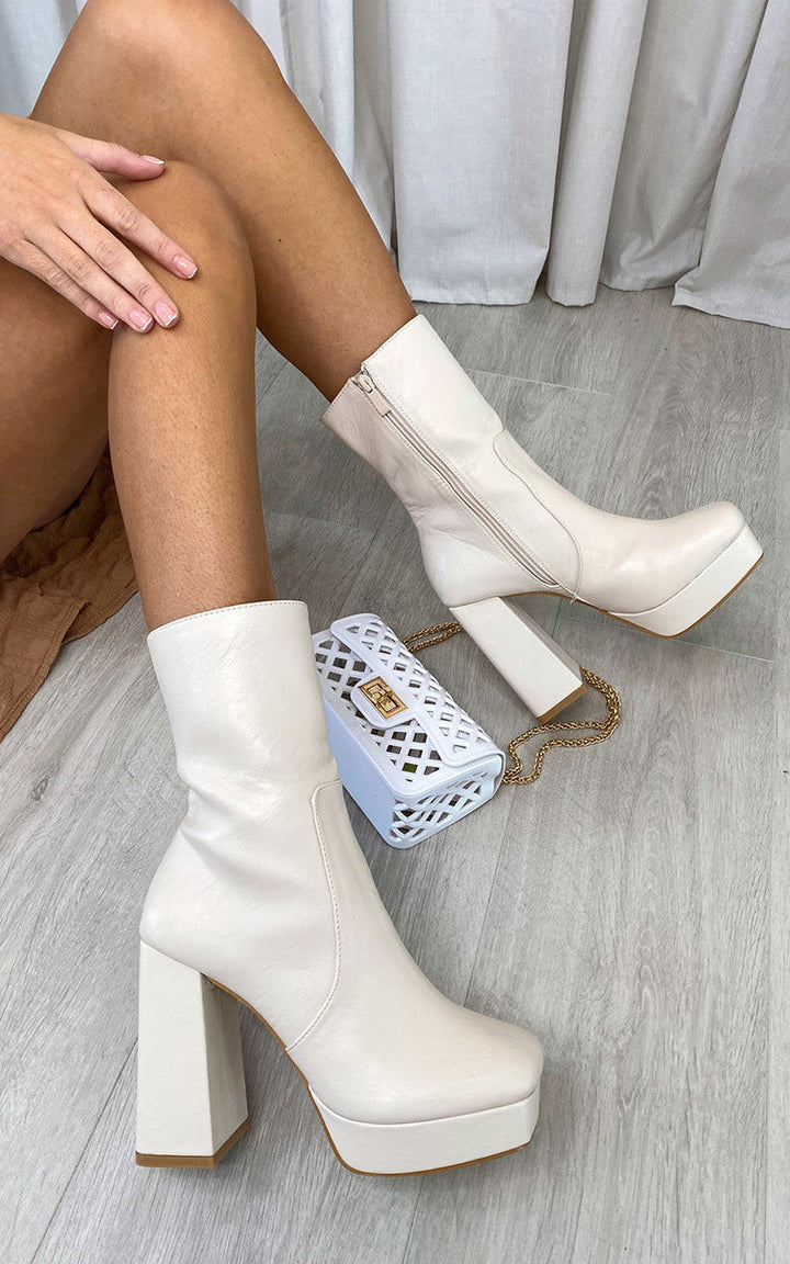 Block Heel Ankle Boots with Zip Detail worn with a white purse, highlighting sleek design and stability, ideal for stylish outings.