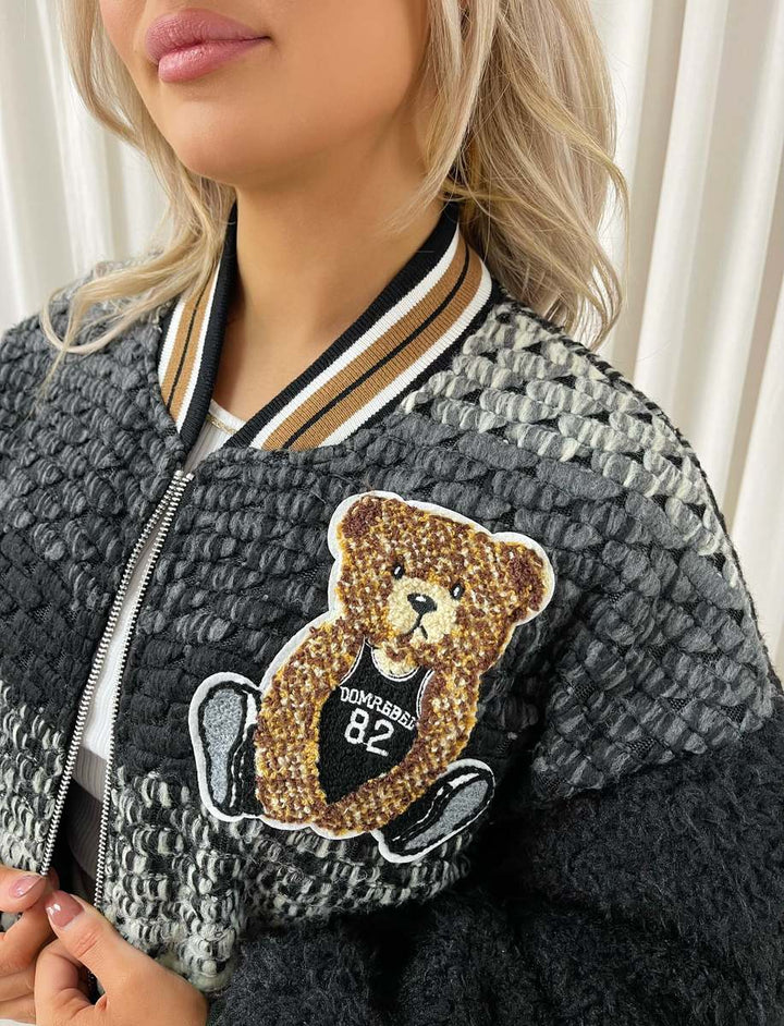 Woman wearing Sylvia Teddy Textured Bomber Jacket with plush teddy bear patch, showcasing its cozy and stylish design, perfect for casual outings.