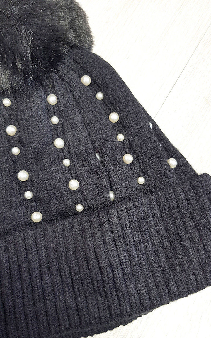 Pom Pom Hat with Pearl Detail: A stylish black beanie adorned with pearls, featuring a soft knit material and a statement pom pom for warmth and elegance.