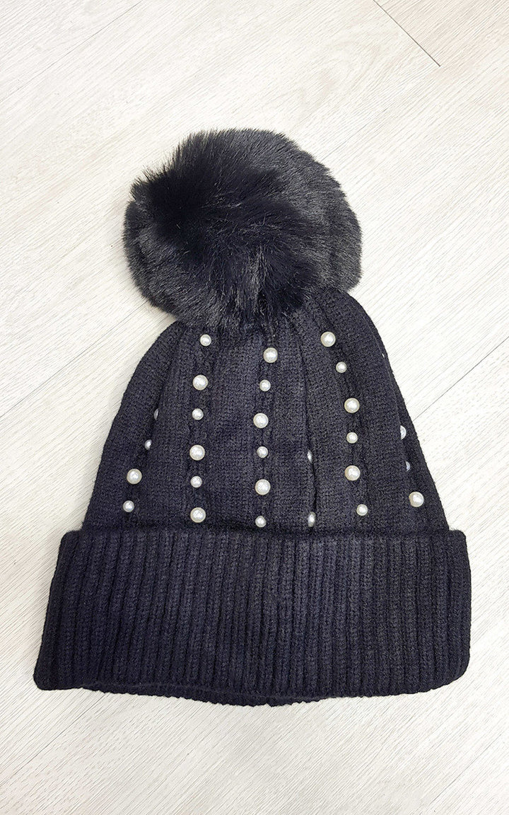 Black Pom Pom Hat with Pearl Detail, featuring a cozy knitted design and decorative pearls, perfect for adding style and warmth during colder months.