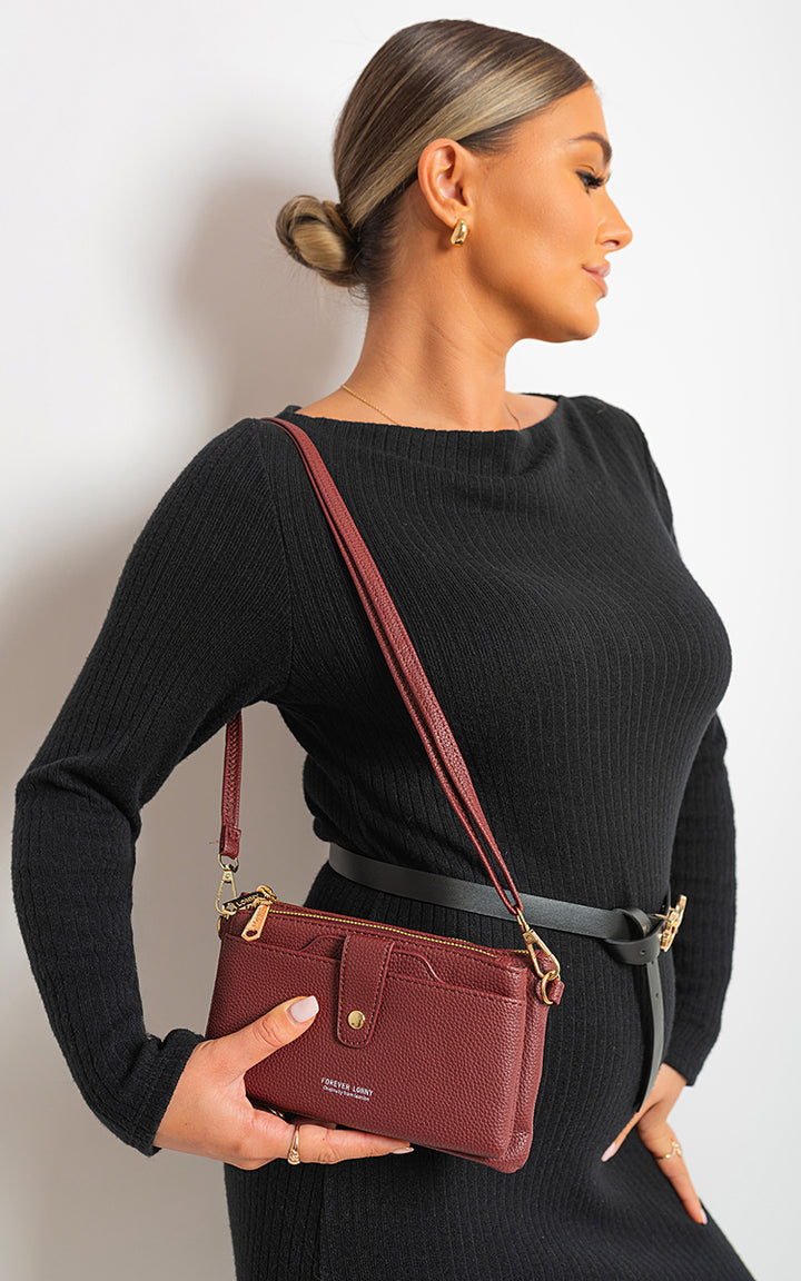 Small Multifunctional Leather Shoulder Bag held by woman in black dress, showcasing its compact design and adjustable strap, ideal for versatile everyday use.