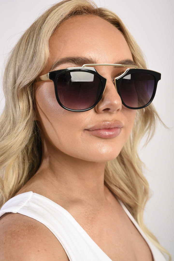 Woman wearing Tori Brow-Bar Cat Eye Sunglasses, showcasing the stylish cat eye shape and modern brow-bar detail, perfect for enhancing any outfit.