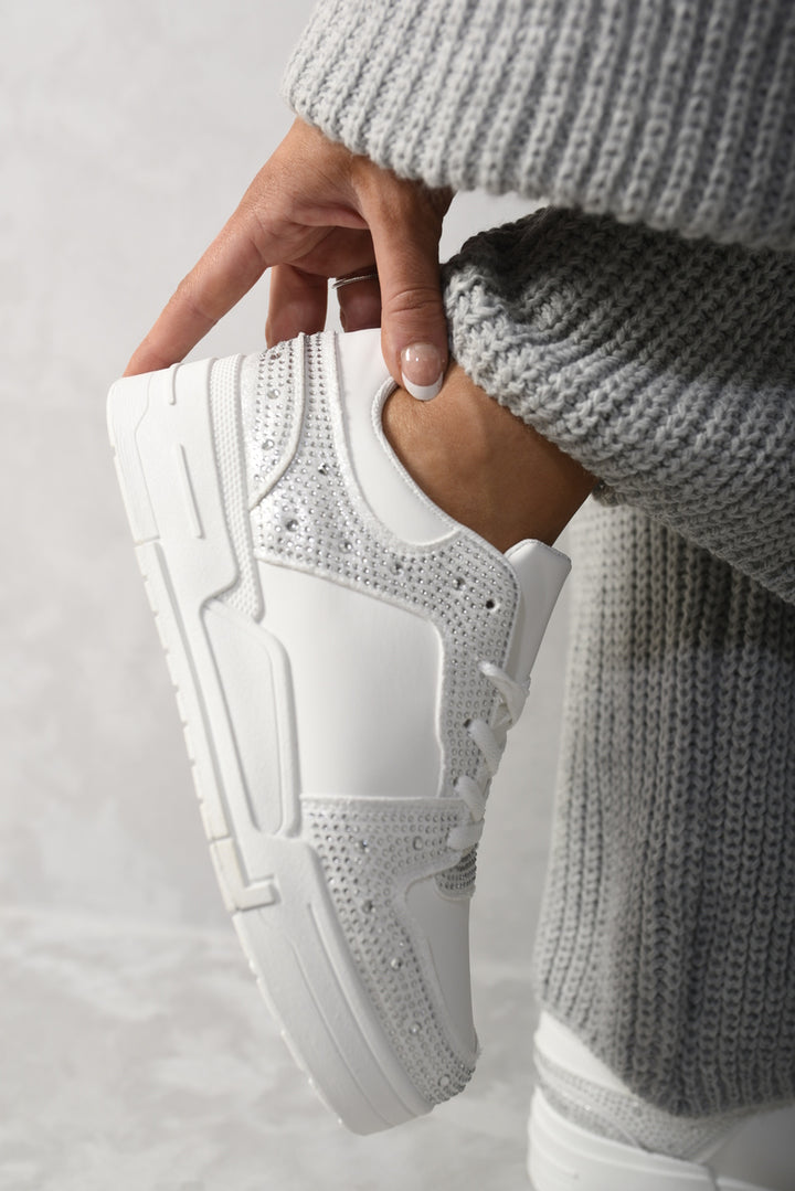 Hand holding Sparkly Crystal Embellished Trainers, showcasing intricate crystal detailing. Perfect for adding glamour to any outfit, aligning with Holiday-clothes.co.uk's stylish offerings.