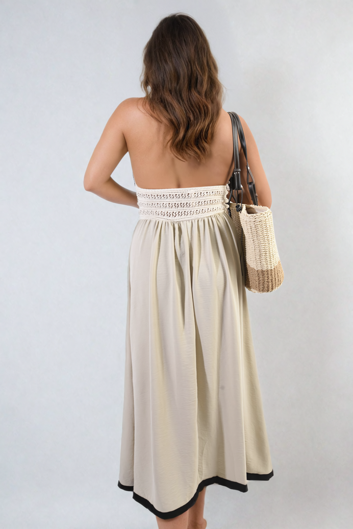 Woman in Crochet V-Neck Halter Backless Maxi Dress, holding purse, showcasing elegant bohemian style with flowing silhouette, perfect for summer occasions.