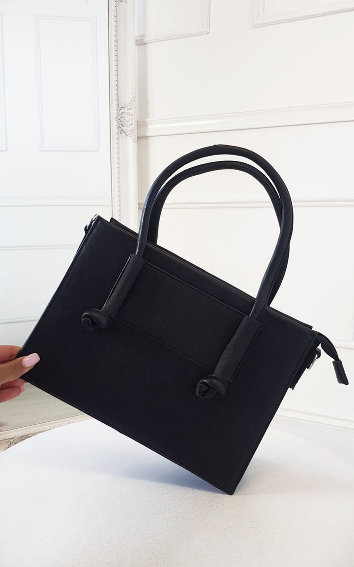 Hand holding the Faux Leather Handbag with zip fastening, handheld and detachable shoulder strap, showcasing its stylish design and silver hardware details.