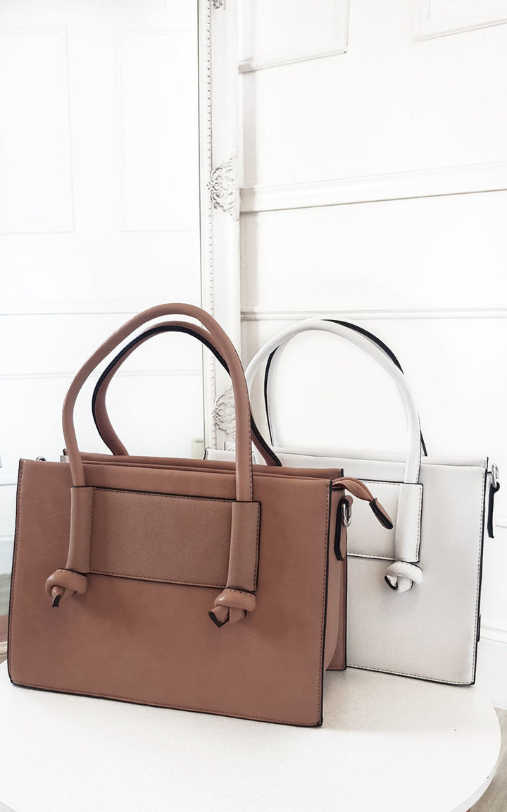 Faux Leather Handbag displayed on a shelf, showcasing its sleek design and silver hardware, with a detachable shoulder strap and multiple compartments.