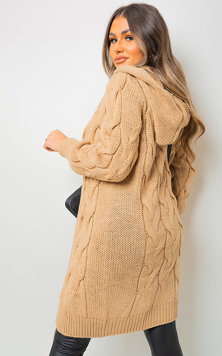 Woman wearing a Chunky Cable Knitted Oversized Longline Hooded Cardigan, showcasing its cozy, layered fit and stylish hood, perfect for casual comfort.