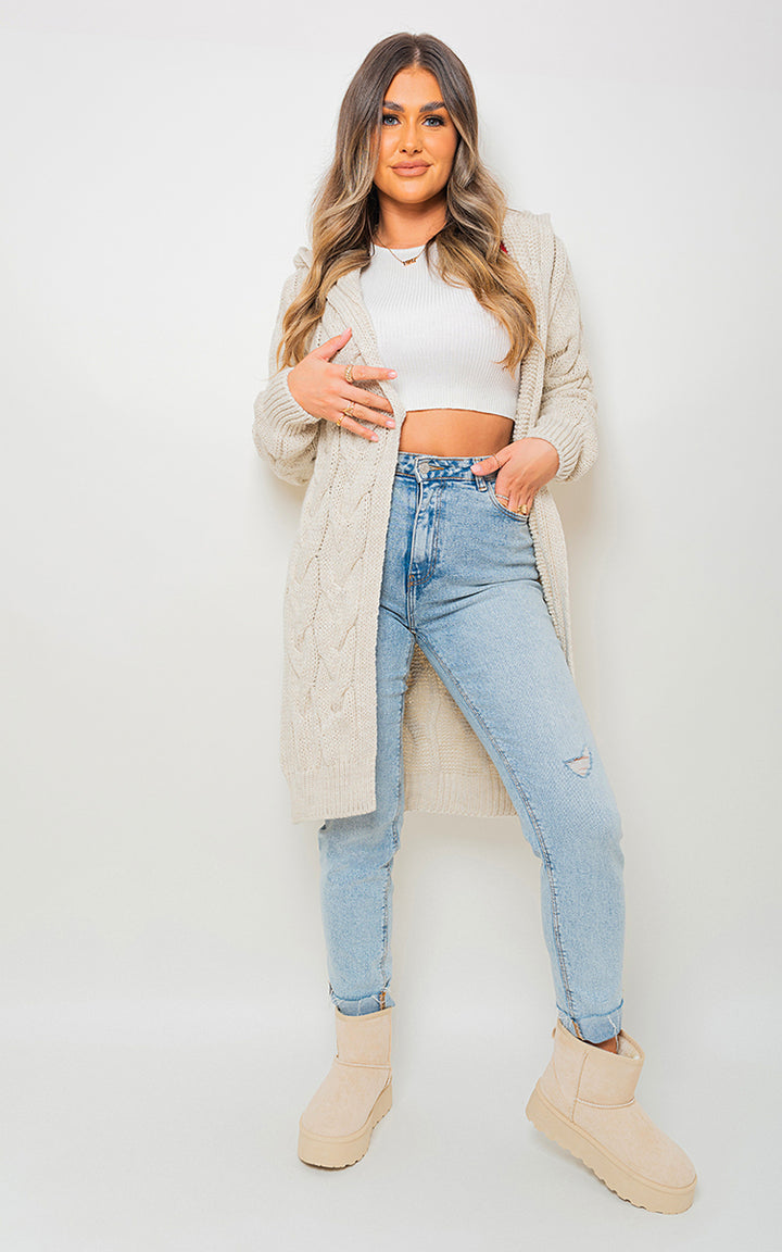 Woman wearing Zoe Chunky Cable Knitted Oversized Longline Hooded Cardigan over jeans, highlighting its cozy and stylish design perfect for layering.