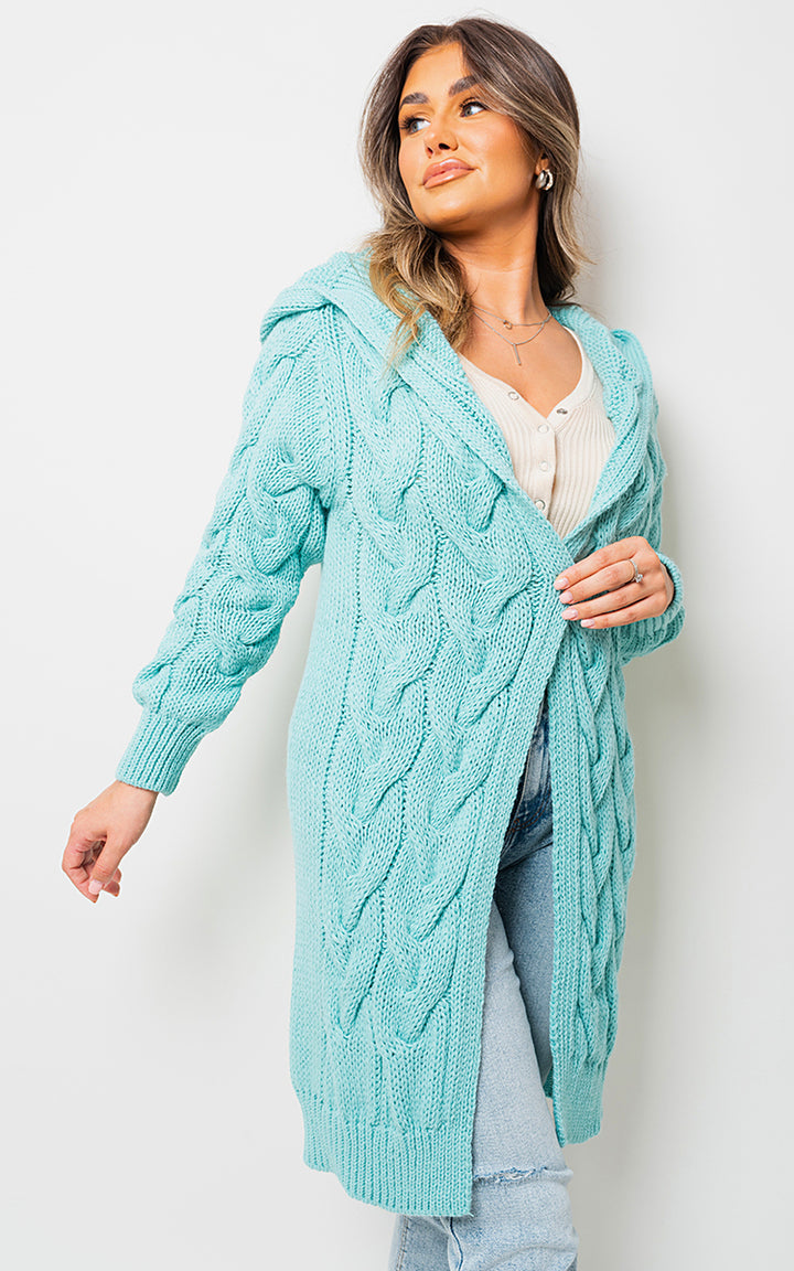 Woman wearing a Chunky Cable Knitted Oversized Longline Hooded Cardigan, showcasing its cozy, layered style perfect for casual, everyday wear.