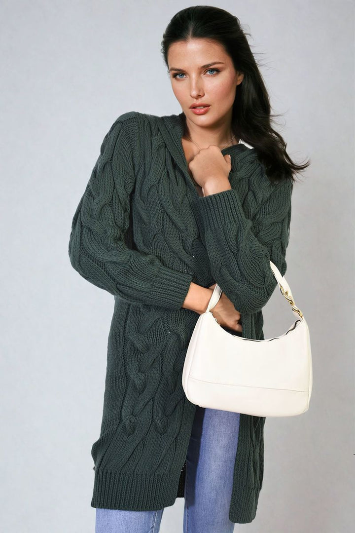 Woman in a chunky cable knitted oversized longline hooded cardigan holding a purse, showcasing cozy, stylish layering essential from Holiday Clothes UK.