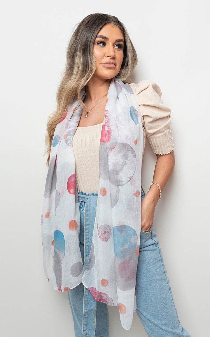 Woman wearing the Summer Wrap Scarf with Printed Large Polka Dots, styled casually over a white sweater, showcasing its playful, versatile design.